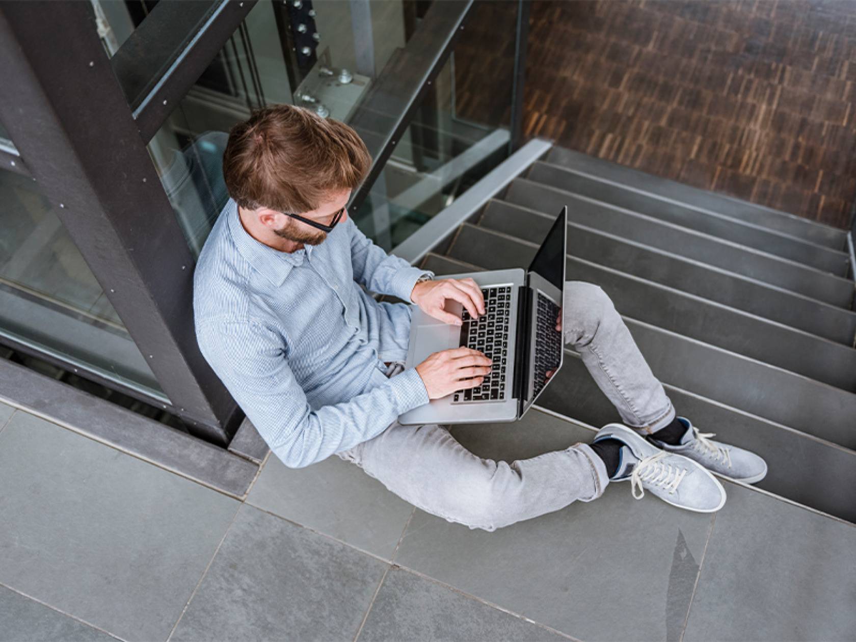 Wiki Schmuckbild 14 Ein Mann sitzt auf einer Treppe und arbeitet an einem Laptop